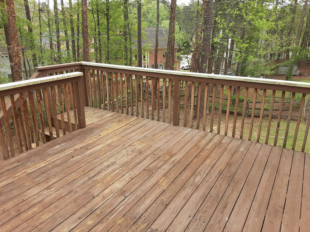 Finished wooden deck with railings overlooking a wooded backyard